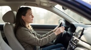 Fokussierte Fahrerin am Steuer als Symbol für Verantwortung im Straßenverkehr nach der Cannabis-Legalisierung: Führerschein zurück und neue Regeln zur Fahrtüchtigkeit.