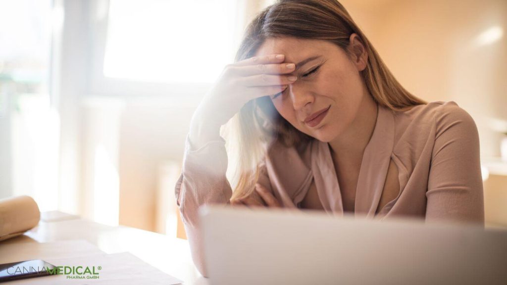 Frau fasst sich an schmerzenden Kopf