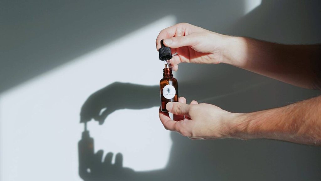 Hände mit Cannabisöl Fläschchen