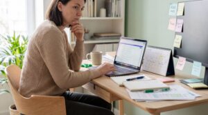 Frau sitzt konzentriert an einem Schreibtisch mit Laptop, Notizen und Kalender – typische Alltagssituation bei ADHS, die zeigt, wie Cannabis gegen ADHS als mögliche Unterstützung zur besseren Struktur und Fokussierung diskutiert wird.