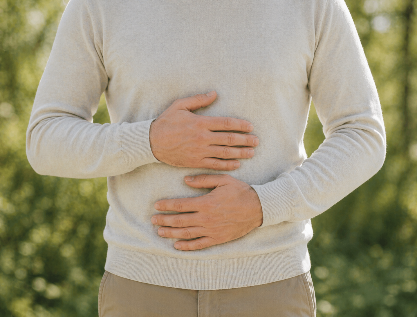 Mann hält sich mit beiden Händen den Bauch als Symbol für Übelkeit oder Magenbeschwerden